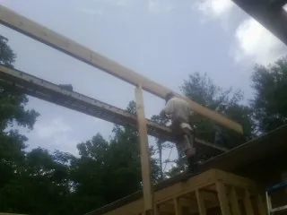 Carpenter setting a ridge beam over a new addition frame — Ice Dam Removal by Roofing Brothers in New Bavaria