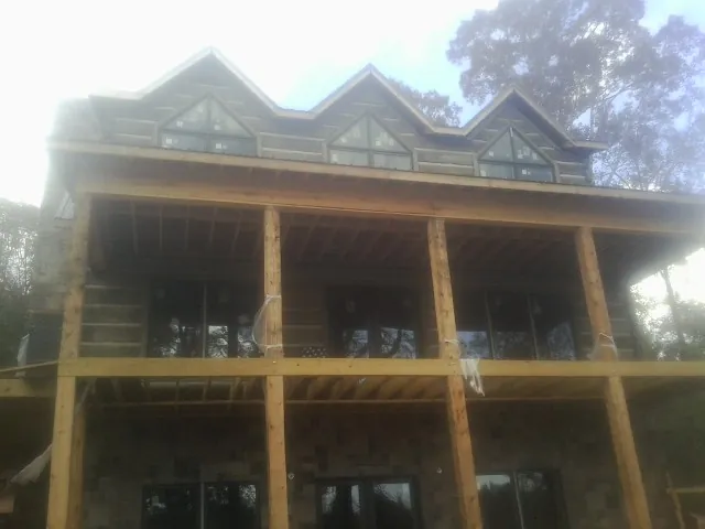 Dormers and porch framing on a large log home under construction — Roof Coating work by our crew in New Bavaria
