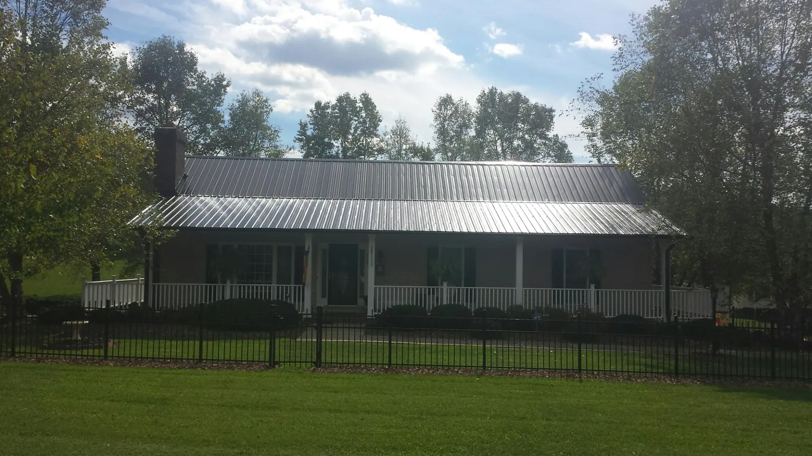 Gray metal roof on a brick ranch with a full width front porch — Gutter Guard Installation work by our crew in New Bavaria