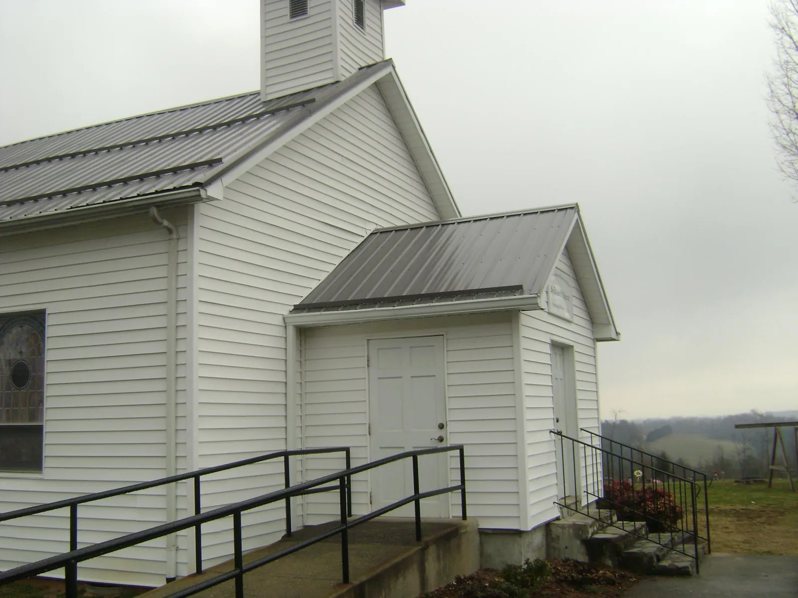 Gray metal roof on a white clapboard church with a steeple in New Bavaria