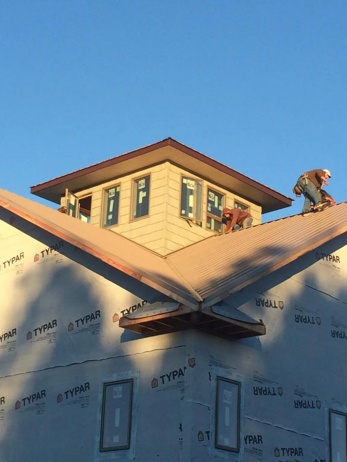 Roofers working around a rooftop cupola on a new metal roof at sunset — Roof Waterproofing in New Bavaria by Roofing Brothers